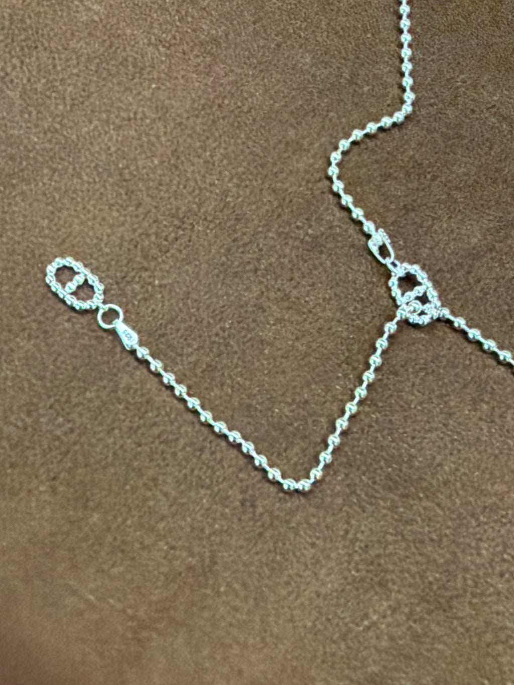Close-up of two textured open-link motifs and the trailing fine chain of the A61 silver-tone necklace.