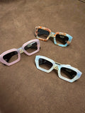 Three glasses-shaped hair clips in pink, pale pearlescent tones and a brown-and-blue mixed pattern on brown fabric.