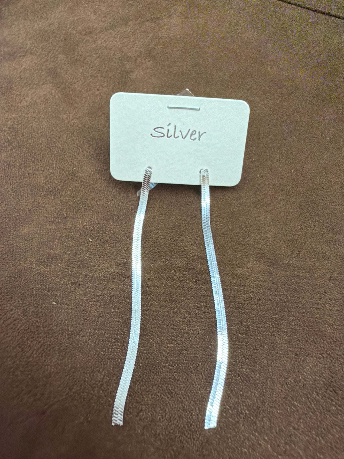 Pair of long silver-tone flat-chain earrings with closely arranged herringbone-like links on a white card marked Silver.