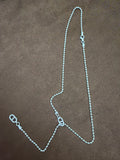 Silver-tone fine-chain necklace with textured open-link motifs and a trailing chain section, arranged on brown fabric.