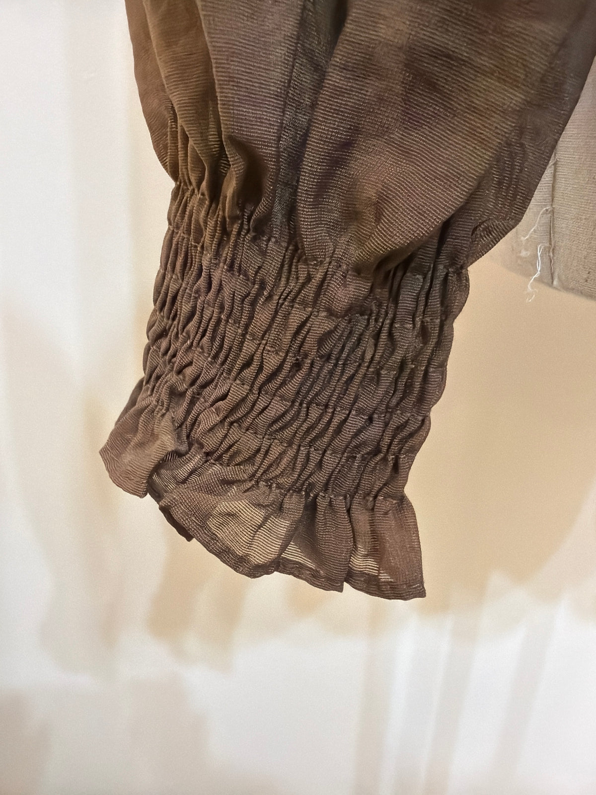 Close-up of the H48 brown blouse sleeve, showing a smocked cuff, ruffled edge and fine fabric texture.