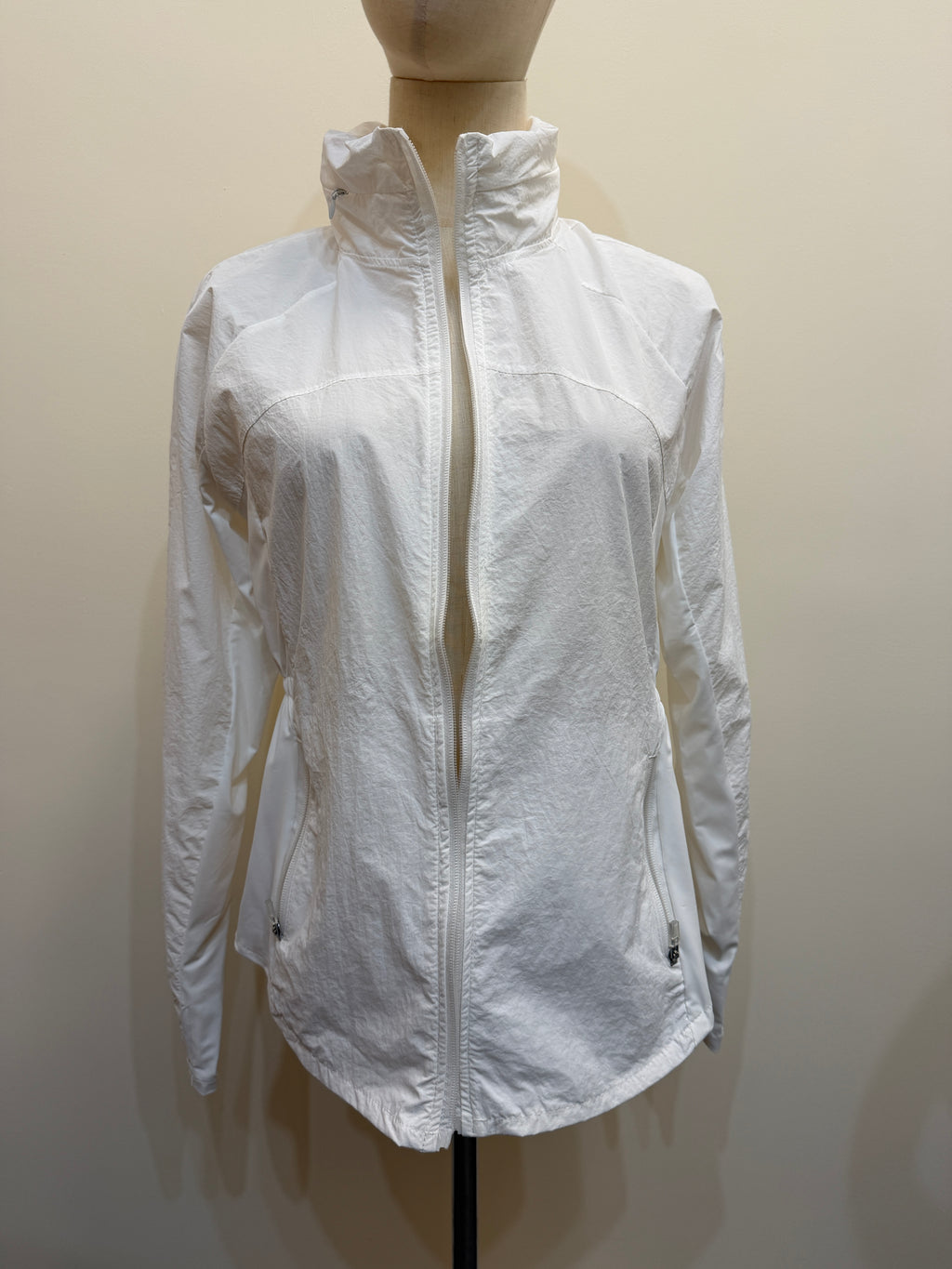 Front view of the H67 white stand-collar jacket on a mannequin, showing a full-length zip, curved panel seams and two zip pockets.