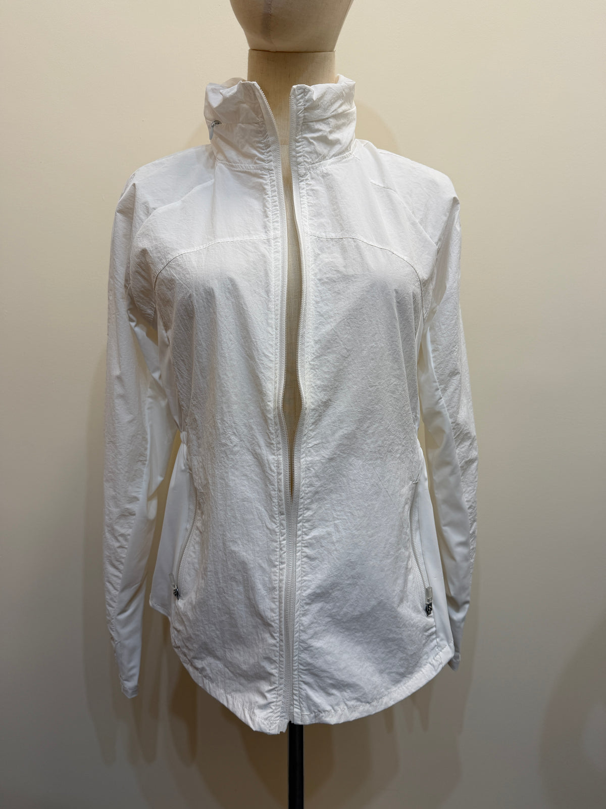 Front view of the H67 white stand-collar jacket on a mannequin, showing a full-length zip, curved panel seams and two zip pockets.
