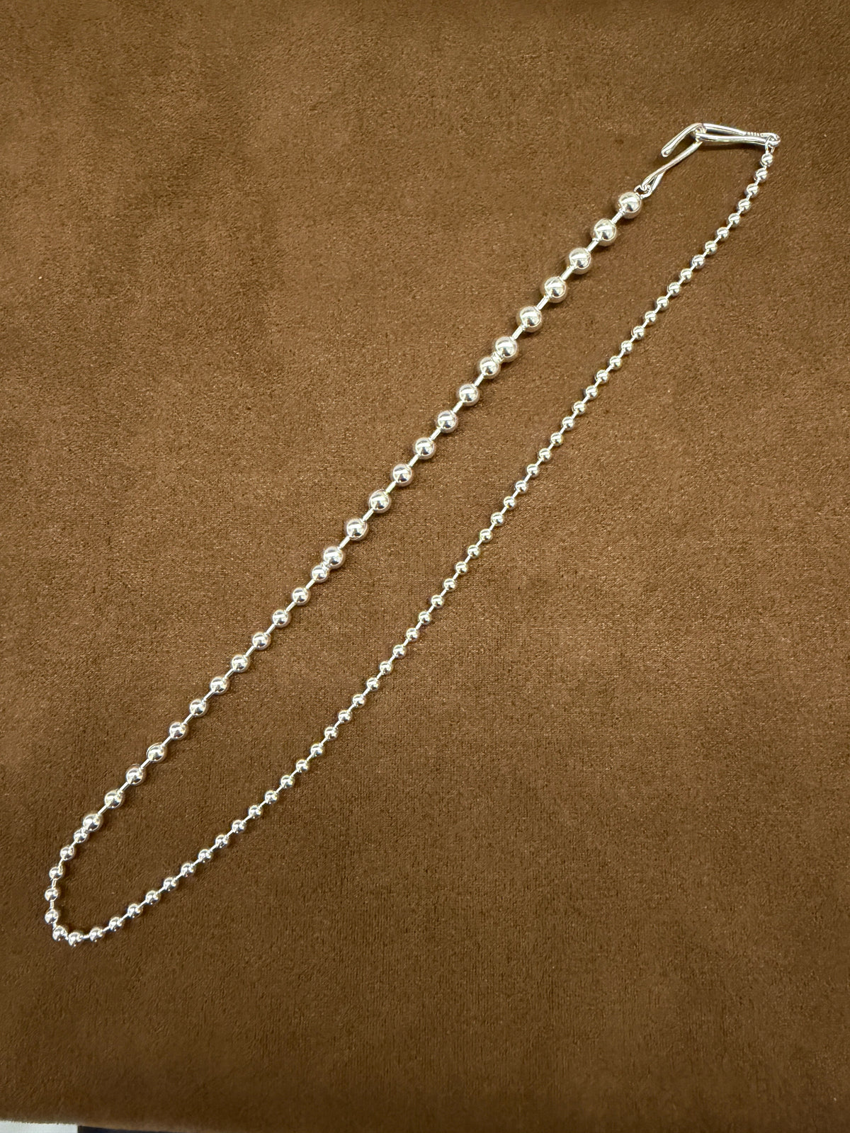 A54 925 sterling silver necklace with graduated polished round beads, 44cm, photographed on brown fabric.