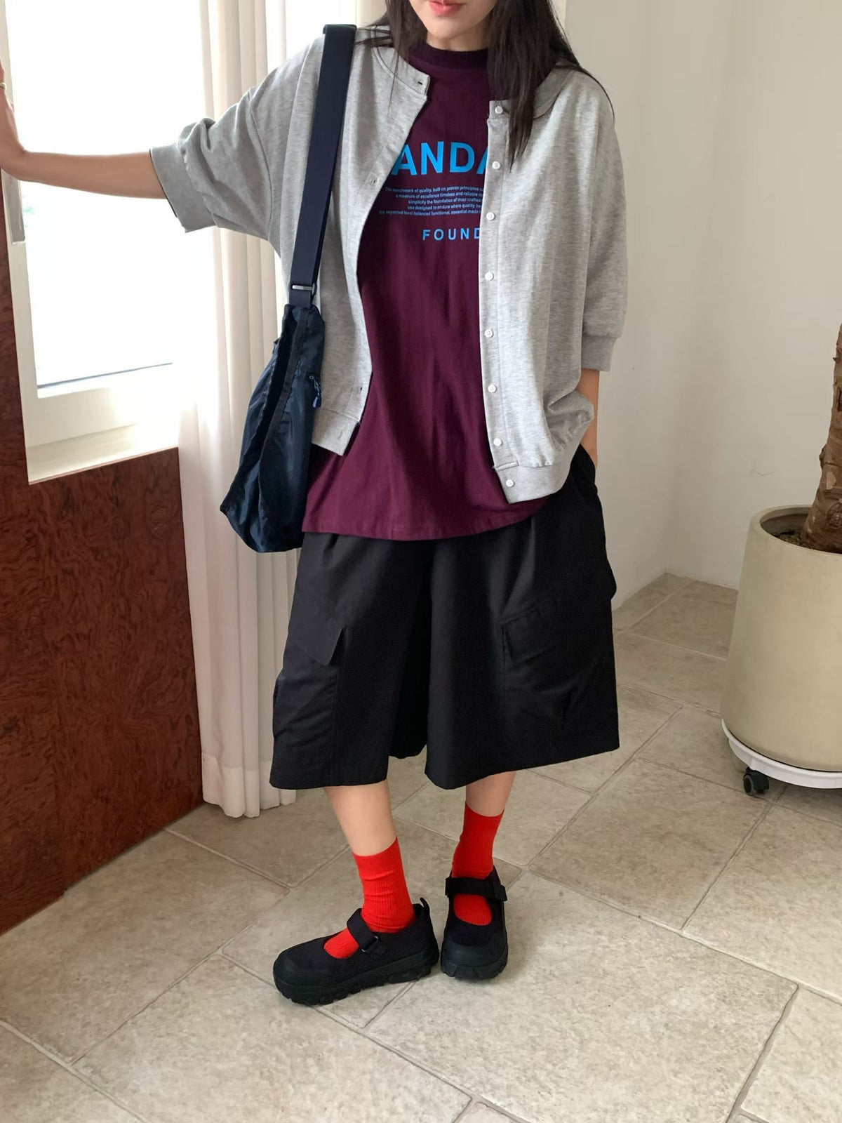 H62 gray half-sleeve jacket worn open over a burgundy graphic T-shirt with black shorts, showing the button front and banded hem.