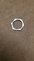 Silver-tone ring with an irregular polygon-shaped outer edge and round inner opening, laid flat on brown fabric.